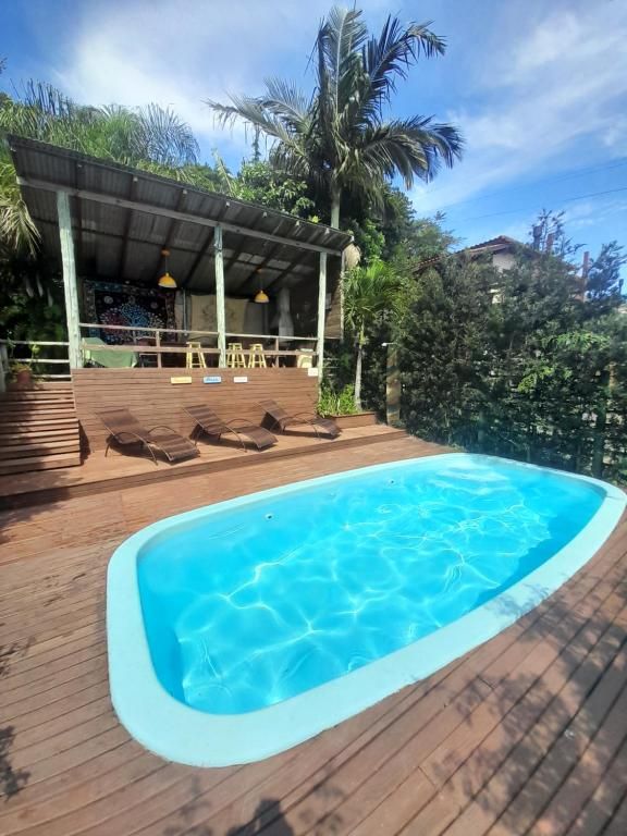 Une piscine avec une terrasse en bois, des chaises longues et un espace salon couvert agrémenté de parasols.