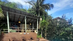 A swimming pool with a wooden deck, lounge chairs, and a covered seating area with umbrellas. - Pousada Baia Rosa (Imbituba)