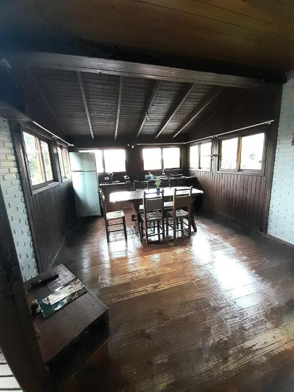 Une pièce spacieuse dotée d’un plancher en bois, d’une grande table à manger et d’un coin cuisine avec un réfrigérateur.