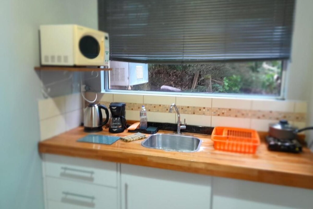 Eine Küche mit Fenster, Mikrowelle, Kaffeemaschine, Spüle und Geschirrgestell.