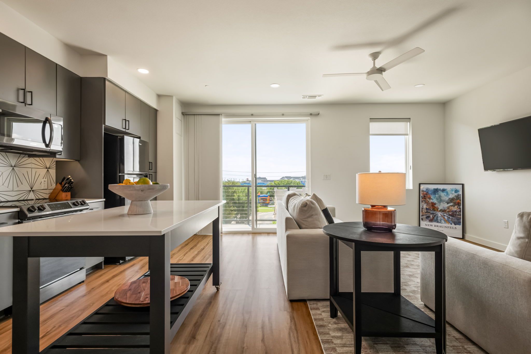 A modern kitchen with a dining area, a sofa, and a TV.