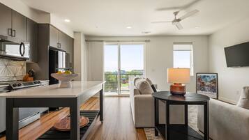 A modern kitchen with a dining area, a sofa, and a TV.