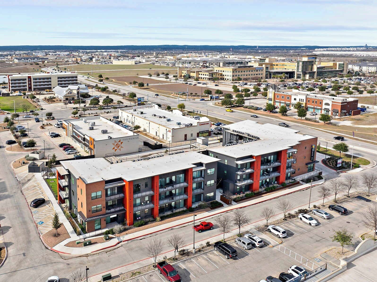A multi-story building with a modern architectural design, featuring a central courtyard and multiple parking spaces.