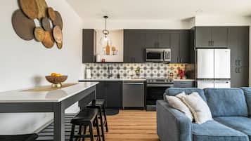 A modern kitchen with dark cabinets, a central island, and a dining area with stools.