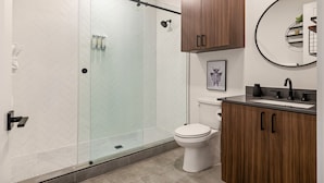 Une salle de bain moderne avec une douche à parois de verre, des toilettes, un lavabo avec un miroir et des meubles en bois.