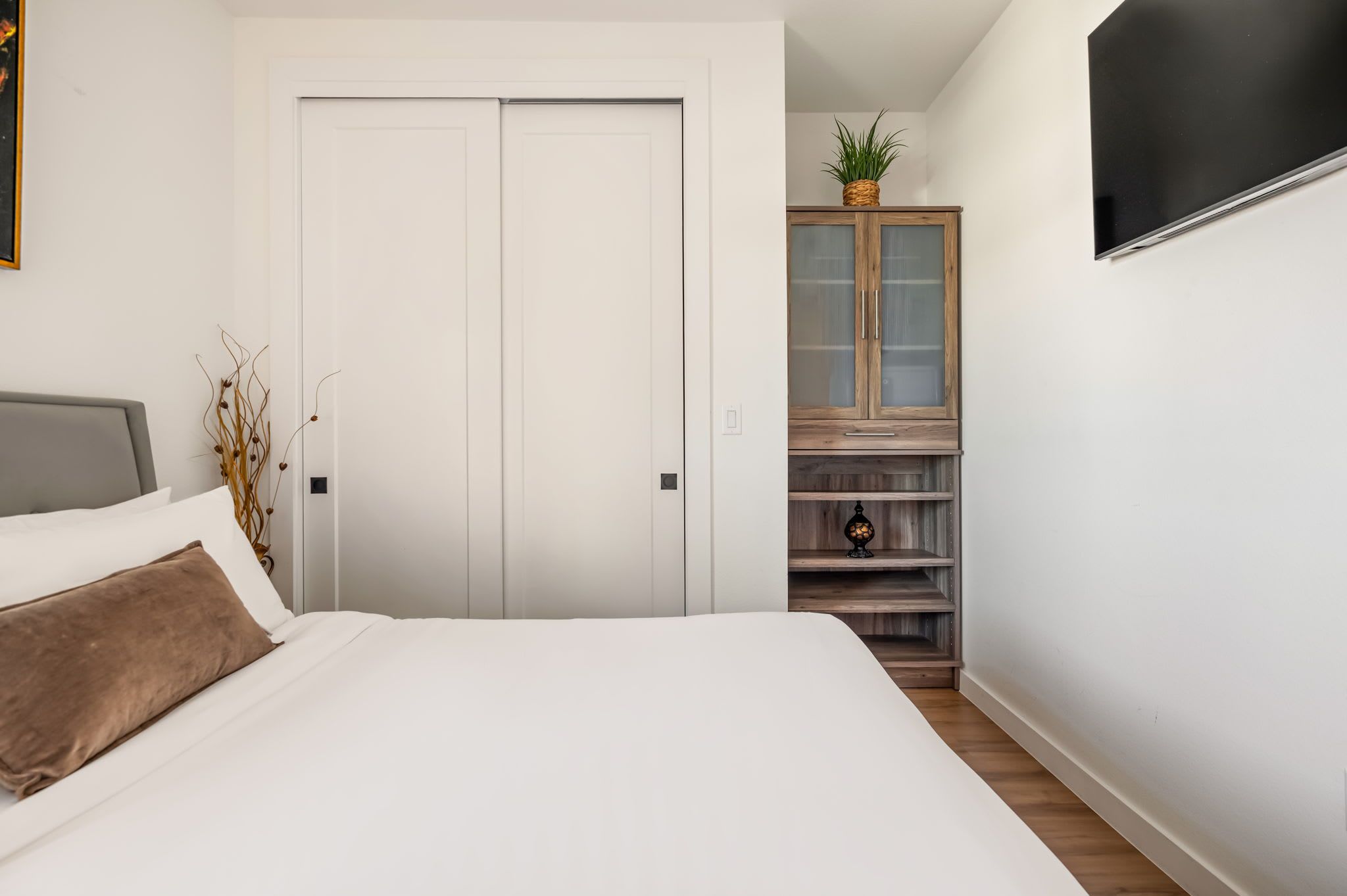Ein Schlafzimmer mit einem Bett, einem Kleiderschrank und einem Fernseher an der Wand.