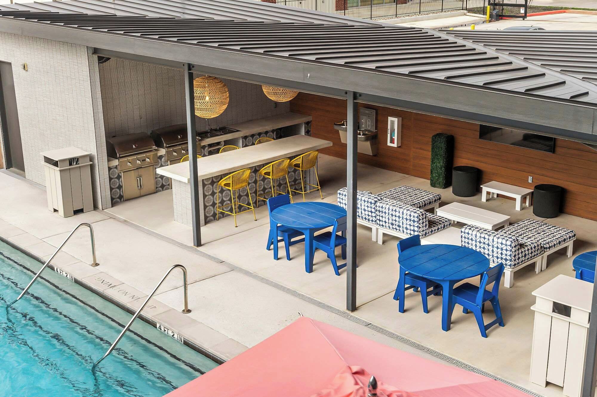 A poolside area with a barbecue, seating, and a covered patio.