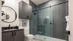 Une salle de bain moderne dotée d’une douche à parois de verre, de toilettes et d’un meuble-lavabo avec un évier.
