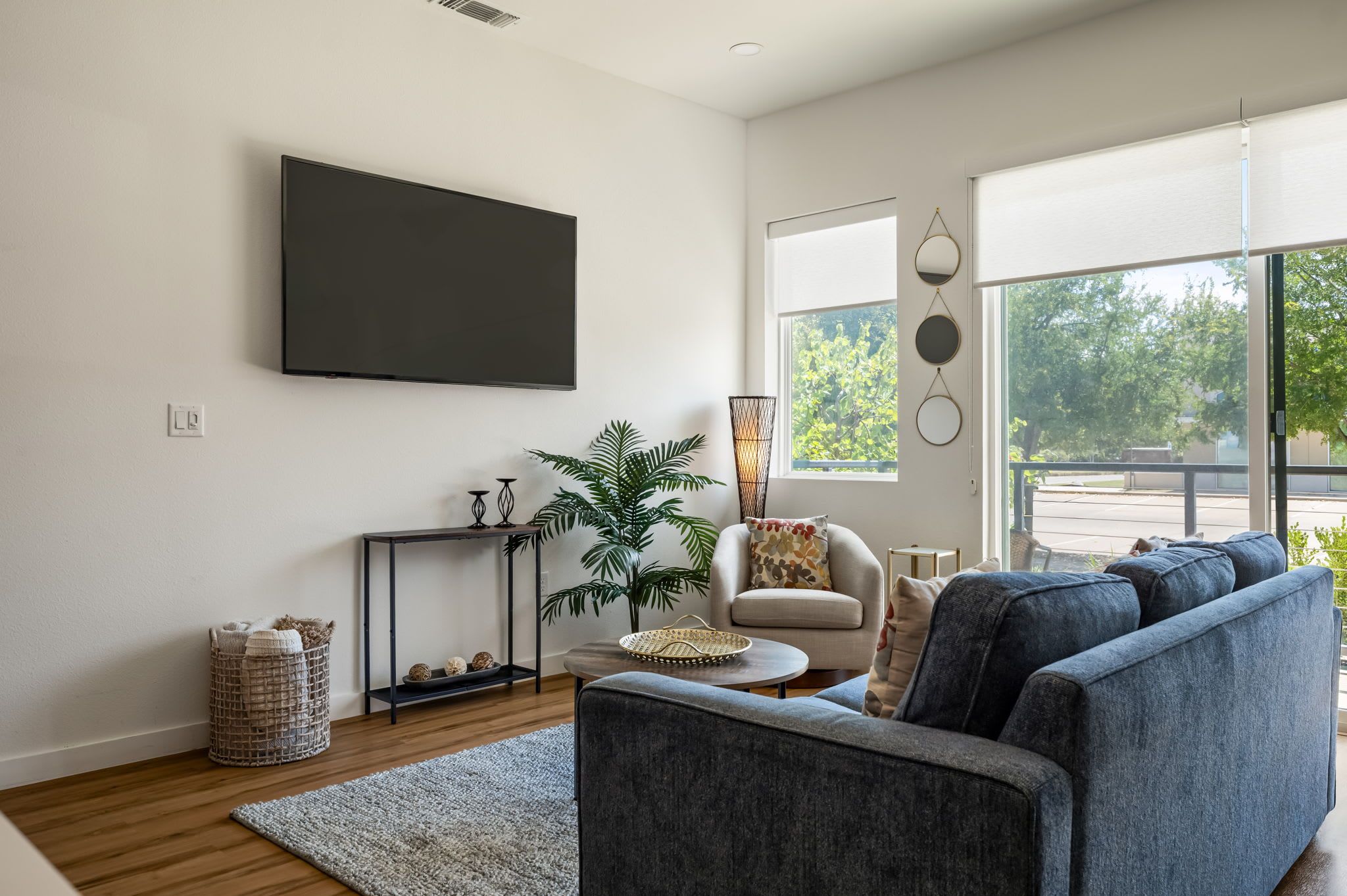 A modern living room with a sofa, a coffee table, a TV, and a large window with a view.