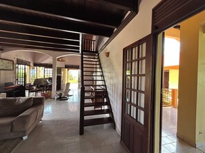 A staircase leading to an upper level, a sofa, and a dining area with chairs and a table. - A Getaway in Gosier: Spacious, Quiet Villa with Ocean and Mountain Views (Le Gosier)