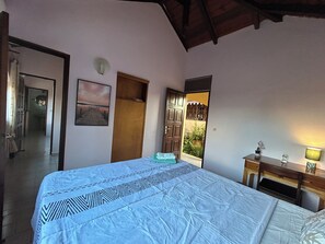 A bedroom with a bed, a door, a painting, and a view of the outside. - A Getaway in Gosier: Spacious, Quiet Villa with Ocean and Mountain Views (Le Gosier)