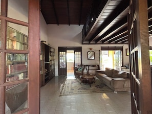 A spacious living area with a high ceiling, a large bookshelf, a sofa, and a patterned rug. - A Getaway in Gosier: Spacious, Quiet Villa with Ocean and Mountain Views (Le Gosier)