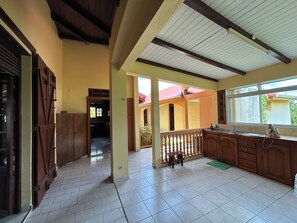 A spacious kitchen with a tiled floor, wooden cabinets, a built-in sink, and a window providing natural light. - A Getaway in Gosier: Spacious, Quiet Villa with Ocean and Mountain Views (Le Gosier)