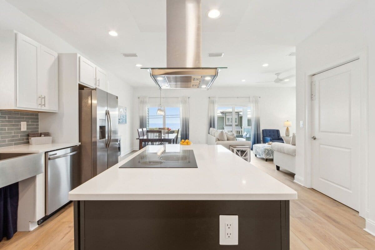 A modern kitchen with a central island, stainless steel appliances, and a dining area with a view.