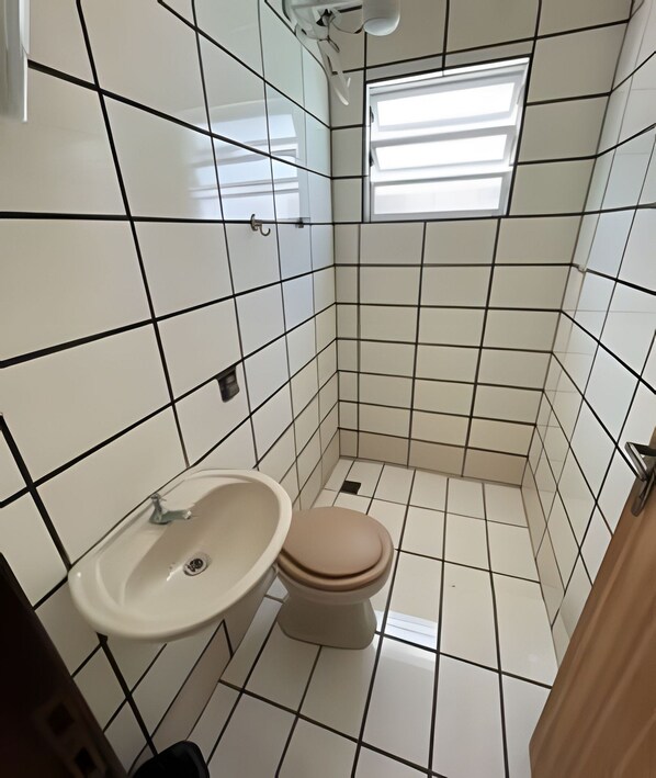 A small bathroom with a toilet, sink, and a window.