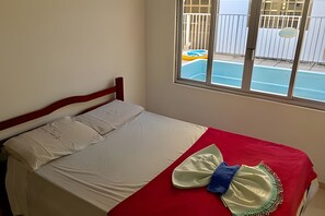A bed with a red and white bedspread, a white pillow, and a blue and white towel.