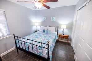 Ein Schlafzimmer mit einem Bett, zwei Nachttischen, einem Deckenventilator und einer Tür.