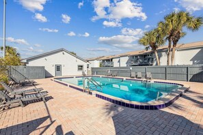 A swimming pool with a tiled edge, lounge chairs, and palm trees. - New Listing - 3BR Condo w/ Pool Walk to Beach (Fernandina Beach)