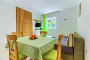 A dining area with a table, chairs, a television, and a window with a view of greenery. - Two-bedroom apartment with garden, only 5 min walking to the Bacvice beach (Split)