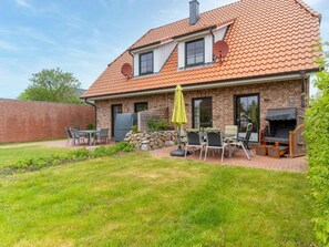 A brick house with a tiled roof, a patio with outdoor furniture, and a stone wall. - Holiday Home With 2 Bedrooms (St. Peter-Ording)