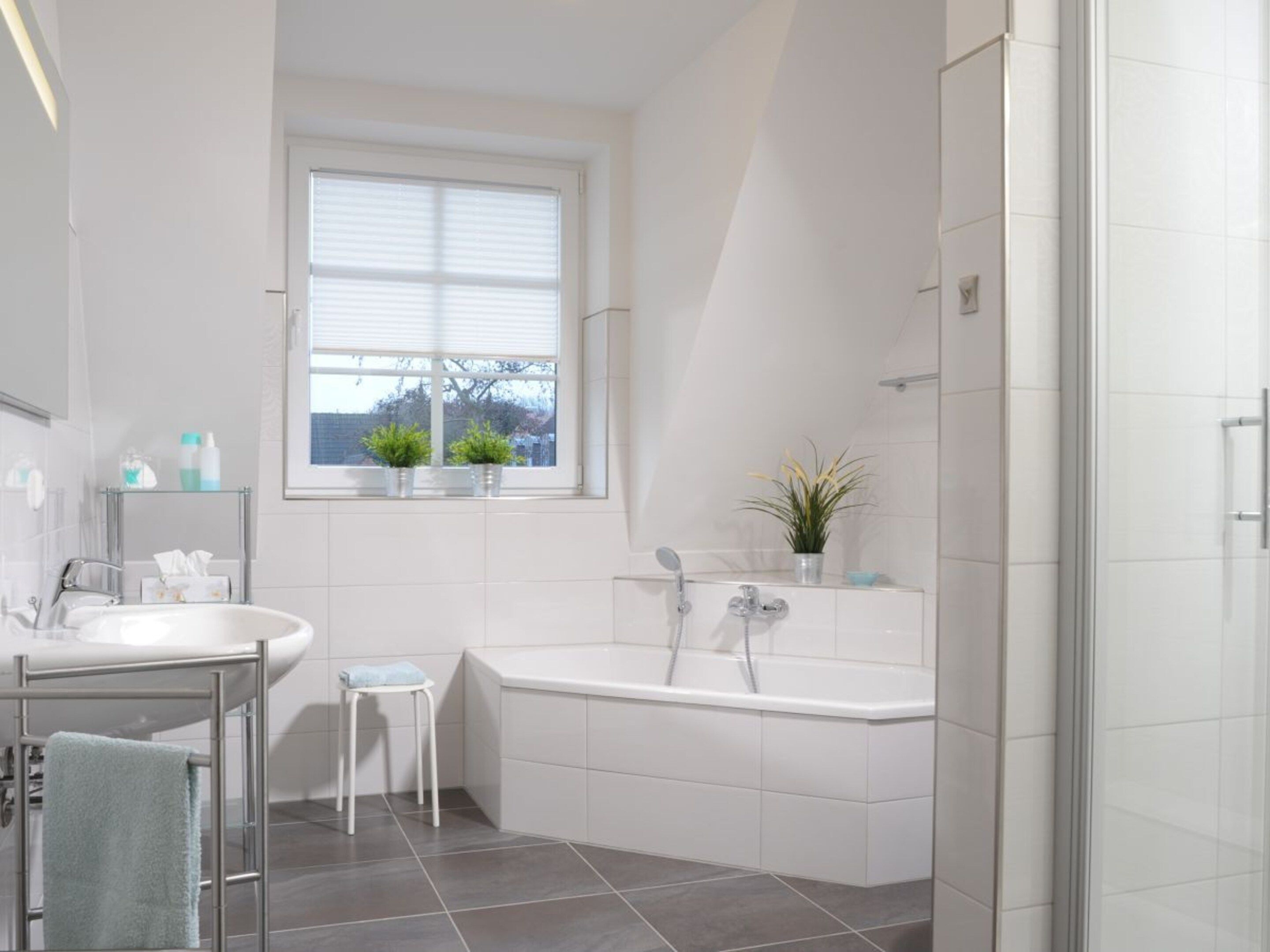 Une salle de bain moderne avec une baignoire, un lavabo et une fenêtre agrémentée de plantes.