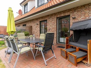 Eine Terrasse mit Tisch, Stühlen, einem Grill und einer Ziegelwand.