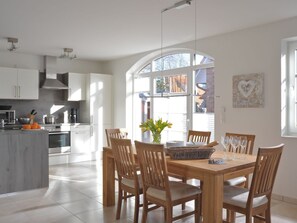 Eine moderne Küche mit weißen Schränken, ein Essbereich mit Holzkästen und ein großes Fenster, das natürliches Licht hereinlässt.
