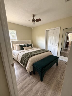 A bedroom with a bed, a bench, a ceiling fan, and a door. - CASA CAMEO European-Inspired Tampa Stay (Tampa)