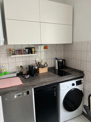 A compact kitchen with a Bosch dishwasher, a washing machine, and a coffee maker on the countertop. - Romantic vacation rental with bathrobes—right in the heart of downtown (Bamberg)
