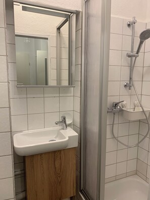 A bathroom with a white sink, a mirror, and a shower enclosure. - Romantic vacation rental with bathrobes—right in the heart of downtown (Bamberg)