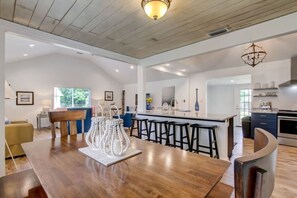 A spacious kitchen with a central island, bar stools, and a dining area with a wooden table. - 4BR Retreat Fire Pit 1 Mile to Beach (Fernandina Beach)