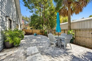 A patio with a table and chairs, surrounded by a wooden fence and potted plants. - The Helm on Elm Beautiful 3/2 Near Downtown (Fernandina Beach)