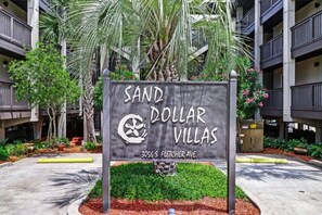 Schild für Sand Dollar Villas, im Hintergrund ein modernes Gebäude.