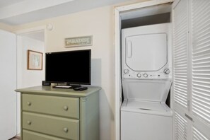 Ein Zimmer mit Fernseher auf einer Kommode, einer Waschmaschine und einer Tür mit dem Schild 'PARADISE'.