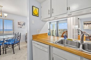 A kitchen with a wooden countertop, stainless steel sink, and white cabinets. - Closest to Beach in Sanddollar! Beachfront w/ Pool (Fernandina Beach)