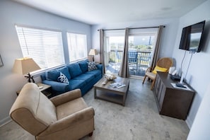 A living room with a sofa, armchair, coffee table, and a TV. - Closest to Beach in Sanddollar! Beachfront w/ Pool (Fernandina Beach)