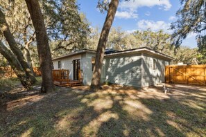 A single-story house with a front porch, surrounded by trees and a wooden fence. - 30+ Day Coastal Cottage Near Downtown (Fernandina Beach)