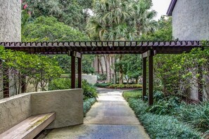 A pathway leading through a garden with a pergola structure. - Omni Amelia Island 2BR Condo Pool Walk to Beach Sleeps 6 (Fernandina Beach)