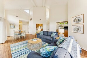 A spacious living area with a sofa, ottoman, and a dining table with chairs. - Omni Amelia Island 2BR Condo Pool Walk to Beach Sleeps 6 (Fernandina Beach)