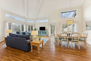 A spacious living room with a sofa, dining table, chairs, and a television. - Omni Amelia Island 2BR Condo Pool Walk to Beach Sleeps 6 (Fernandina Beach)