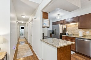 A modern kitchen with granite countertops, stainless steel appliances, and wooden cabinets. - Dog-friendly 3BR Walk to Beach Pool (Fernandina Beach)