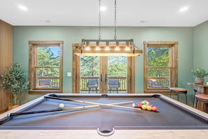 A pool table with a view of a balcony and outdoor scenery. - New Build w/ Views, Hot Tub, & Sauna. Sleeps 16 (Massanutten)
