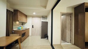 Cozinha compacta com geladeira, pia e armários de madeira.
