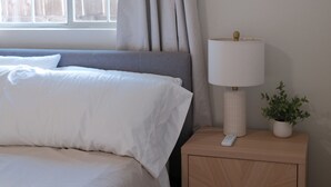 Un dormitori amb un llit, una nitlínia amb una làmpada i una finestra amb cortines.