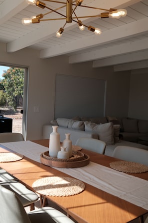 A modern living room with a wooden dining table, a sofa set, and a ceiling light fixture. - Modern SD Home / Sleeps 6 / Fast WiFi / Beach within 10 miles / Games + BBQ (San Diego)