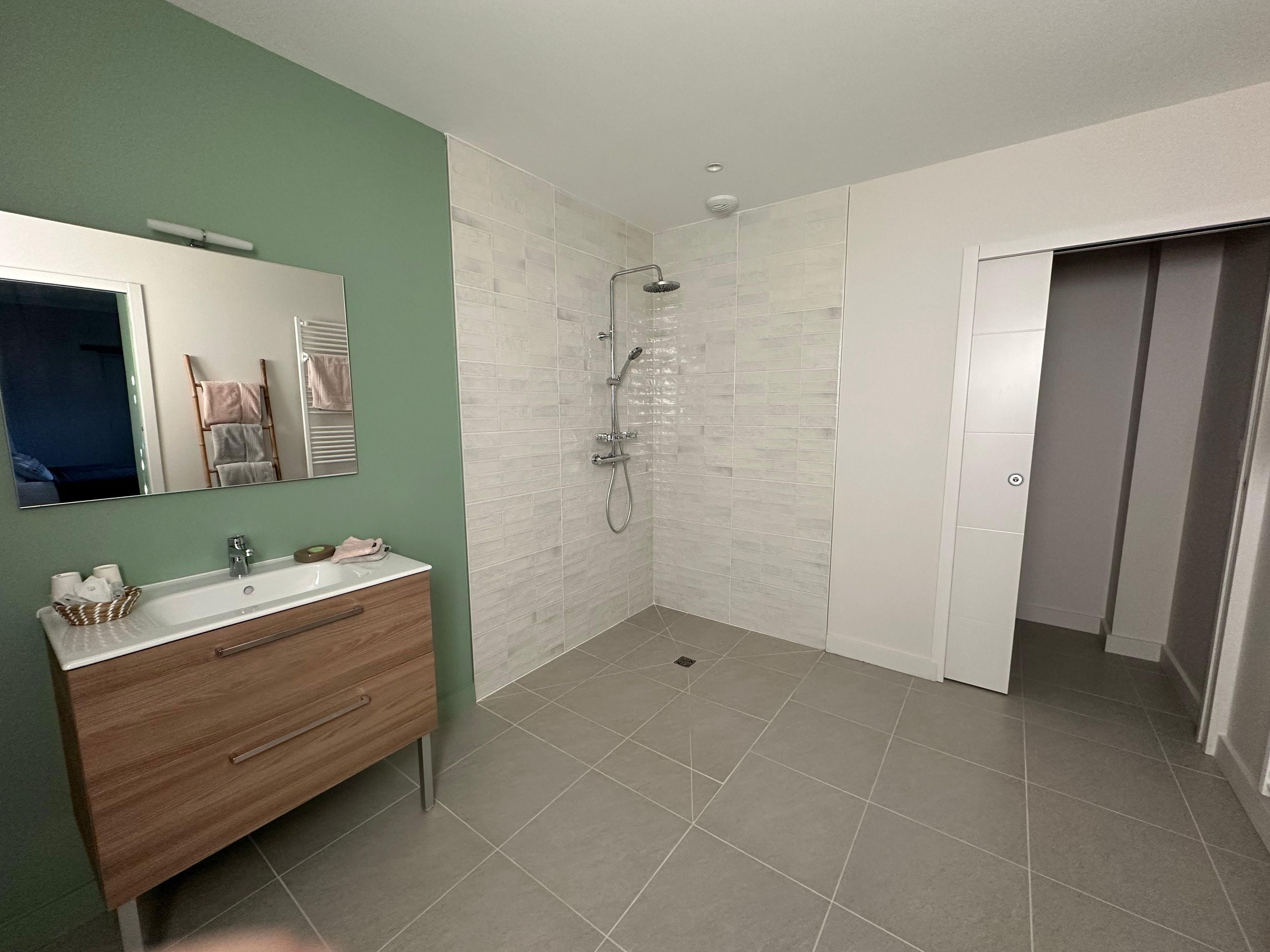 A bathroom with a wooden vanity, a shower, and a mirror.