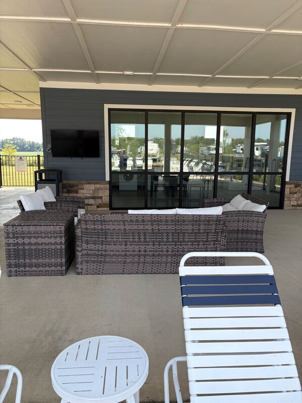 An outdoor patio with a sectional sofa, a round table, and a lounge chair.