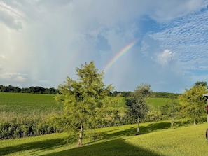 A rural landscape with a rainbow, trees, and open fields.
