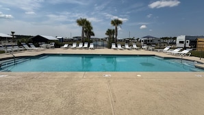 A swimming pool with lounge chairs and palm trees, surrounded by RVs and buildings. - RV Resort, Back-In Full Hookup, 3 Pools, Snowbirds, Kids, Pets (Foley)