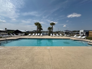 A swimming pool with lounge chairs and palm trees, surrounded by RVs and buildings. - RV Resort, Back-In Full Hookup, 3 Pools, Snowbirds, Kids, Pets (Foley)